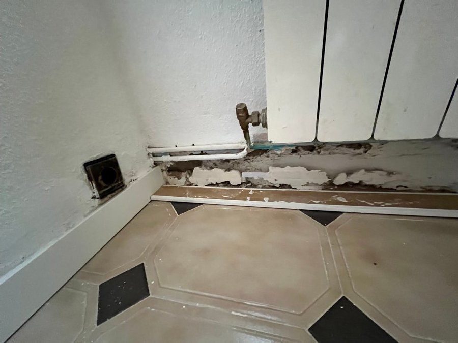 Humedad real detrás del radiador del piso de Zaragoza: pintura levantada y pared dañada