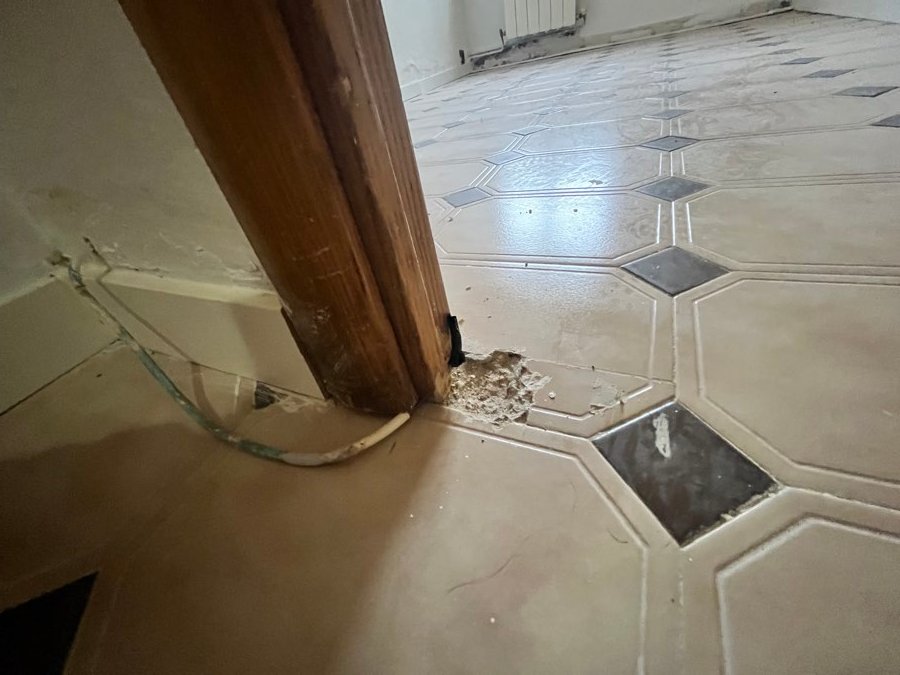 Suelo levantado y baldosas rotas junto al marco de una puerta del piso de Zaragoza